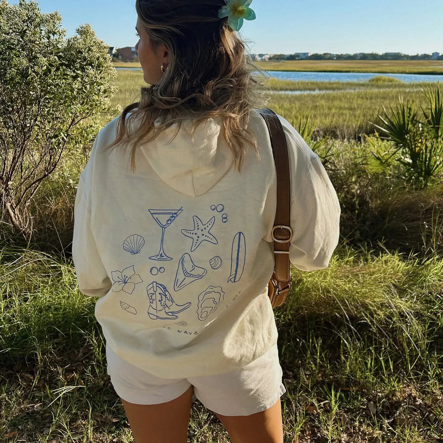 Person wearing a white hoodie with blue graphics in a natural setting