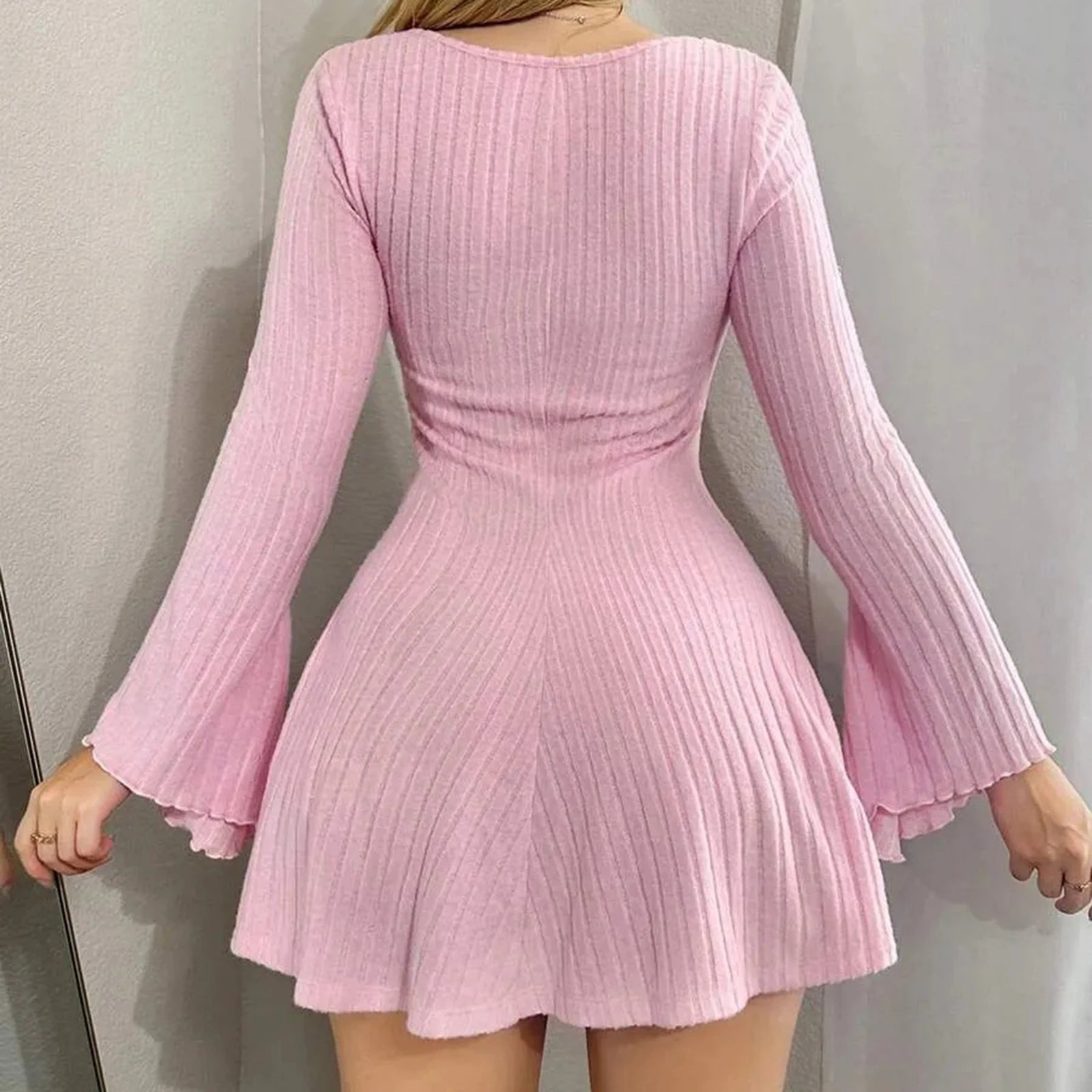 Pink ribbed dress with long sleeves on a plain background