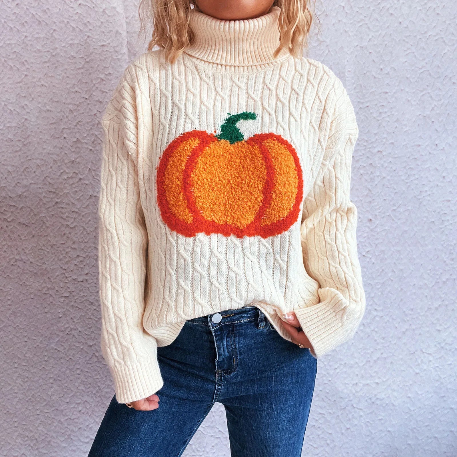Person wearing a cream sweater with a pumpkin design