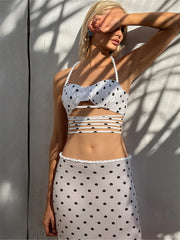 Woman wearing a polka dot bikini set against a white wall.
