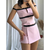 Person wearing a pink outfit with black accents in a room setting.