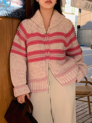 Person wearing a pink and red striped knitted cardigan outdoors.