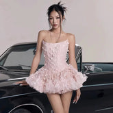 Women's light pink strapless mini dress with a fitted bodice and a voluminous, layered ruffled skirt.