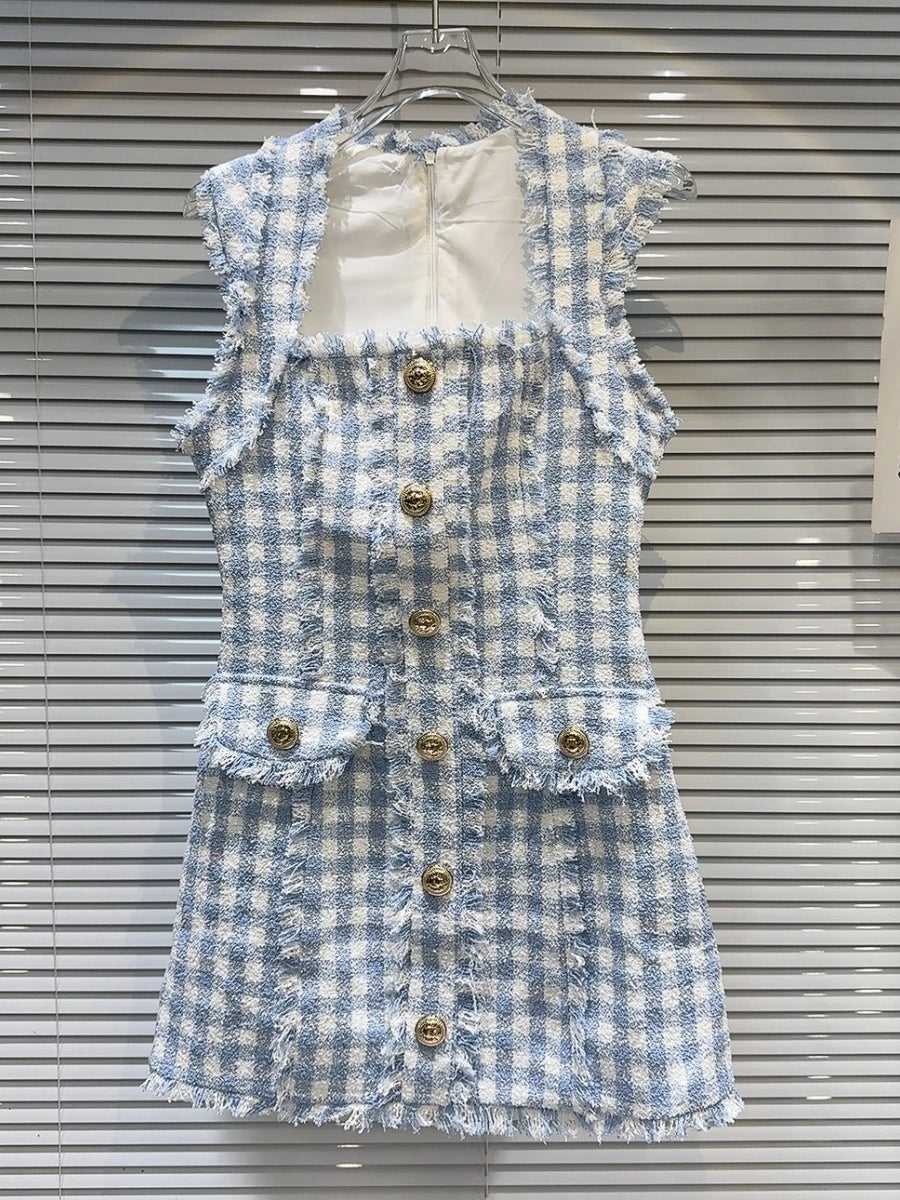 Blue and white checkered dress with gold buttons on a hanger against a window background