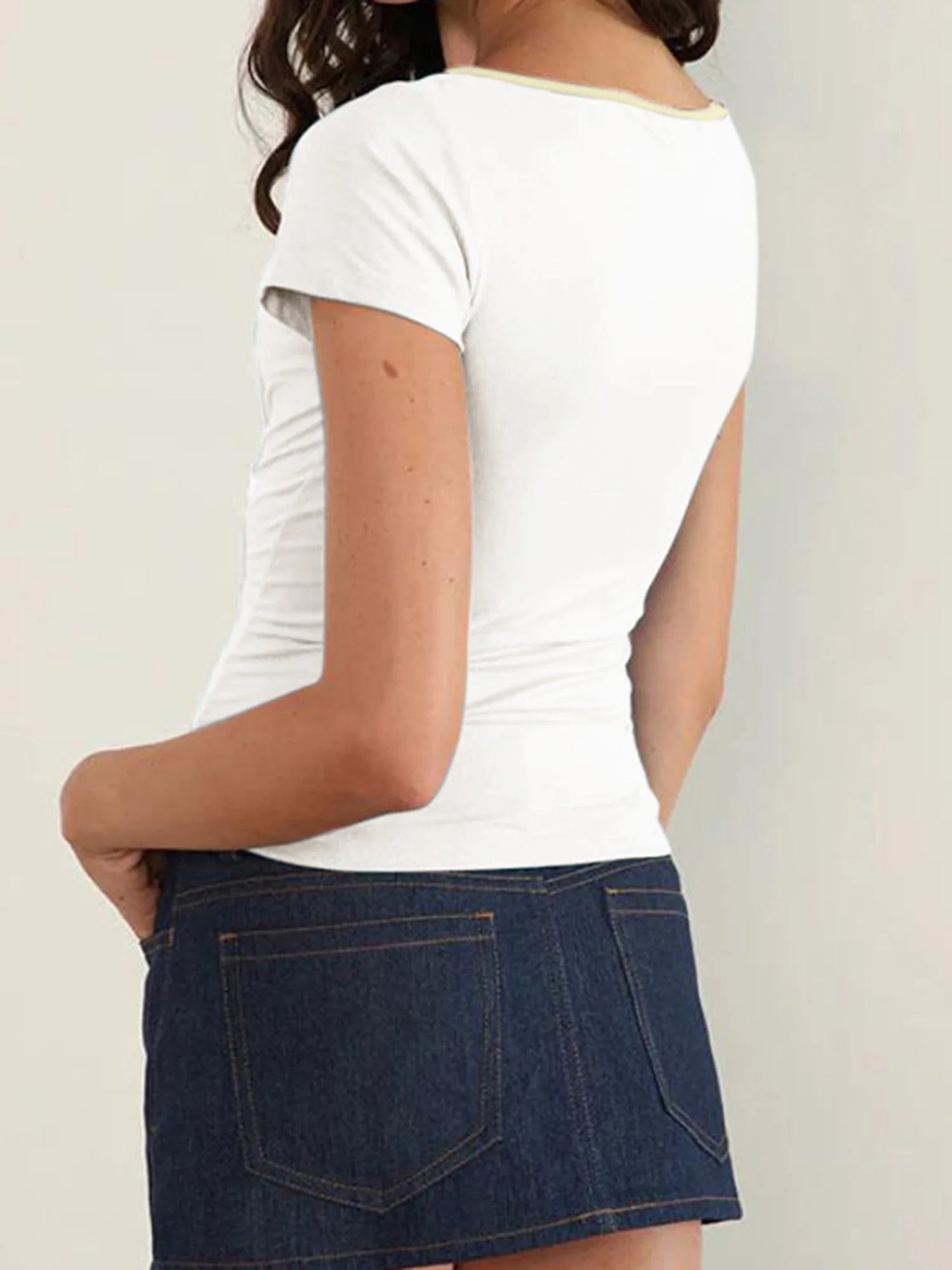 Person wearing a white t-shirt and blue denim skirt- back