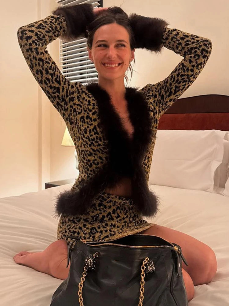 Person wearing a leopard print outfit with fur accents sitting on a bed.