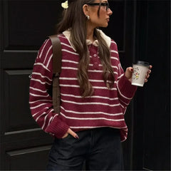 Person wearing a maroon and white striped sweater holding a coffee cup.