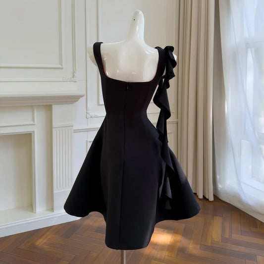 Back view of a black mini dress on a mannequin, showing the square neckline and the continuation of the ruffled sash detail.
