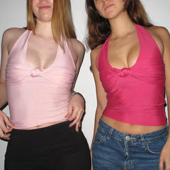 Two women wearing pink halter tops against a plain background