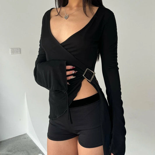 Person wearing a black long-sleeve top with a unique cutout design and black shorts against a plain background.