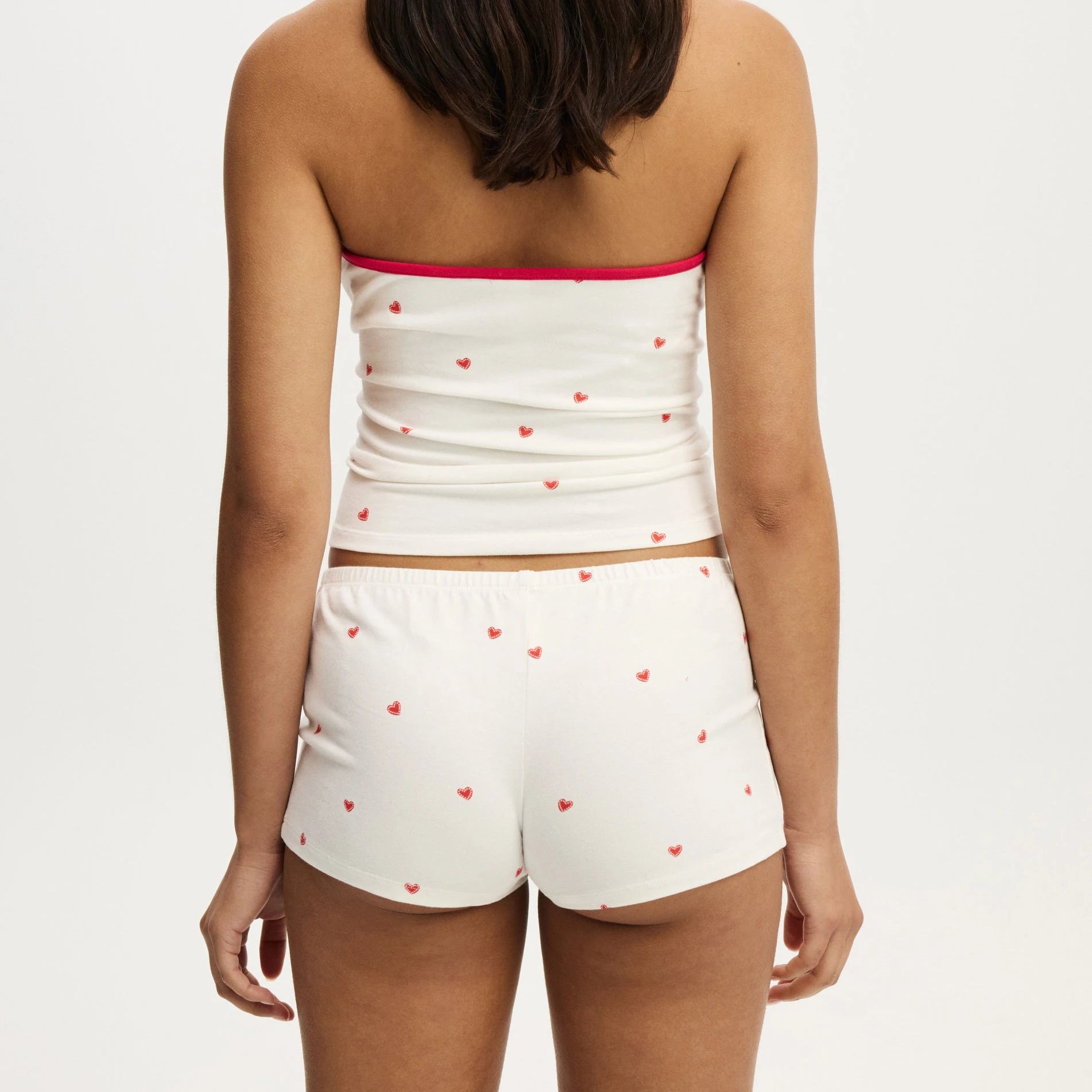 White strapless top and shorts set with red heart patterns on a plain background