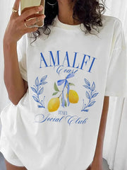 A woman wearing a comfortable graphic t-shirt featuring an Amalfi Coast design, paired with shorts for a casual look.