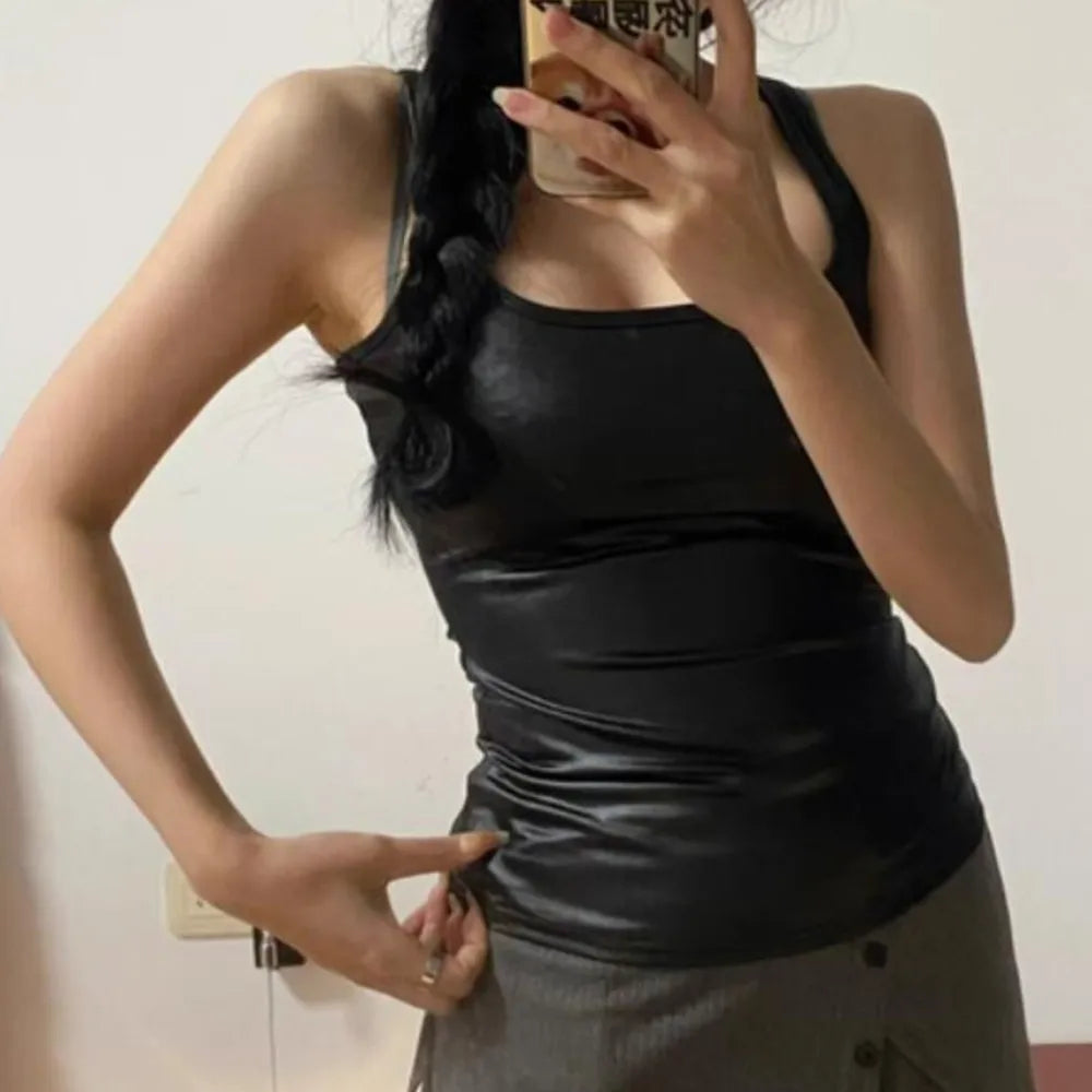 Person wearing a black sleeveless top and gray pants, taking a mirror selfie.