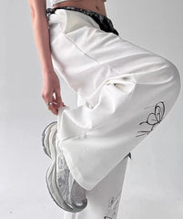 White satin skirt with black butterfly design worn by a person on a light gray background.