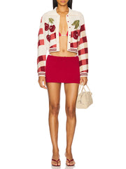 Woman wearing a red and white striped cardigan with cherry designs and a red skirt 
