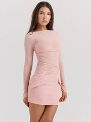 Woman wearing a pink long-sleeve dress on a light gray background