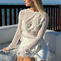 Woman in a white lace dress sitting on a white couch with a scenic background