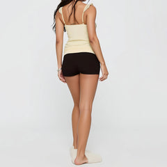 Woman wearing a beige tank top and black shorts