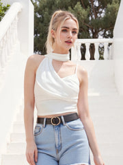 Woman wearing a white halter top and light blue jeans outdoors.