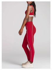 Person wearing red athletic leggings with a white stripe- side details
