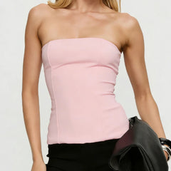 Woman wearing a pink strapless top against a plain background