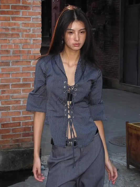 Woman wearing a blue striped shirt with a unique design in an urban setting