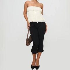 Woman wearing a white strapless top and black pants 