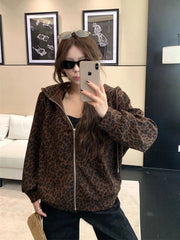 Person wearing a leopard print jacket taking a mirror selfie in an indoor setting.