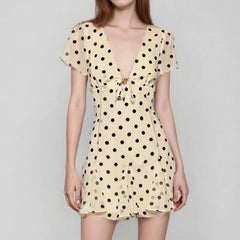 Beige dress with black polka dots on a gray background