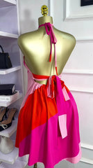 Mannequin wearing a colorful dress with a pink and red design in a store setting.