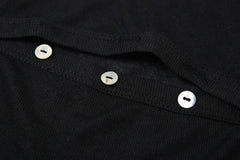 Close-up of the button closures and slit design on a trendy black top.