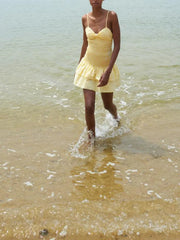 Woman in a yellow dress standing in shallow water at the beach