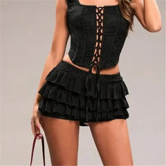 Black lace-up top and ruffled shorts on a neutral background