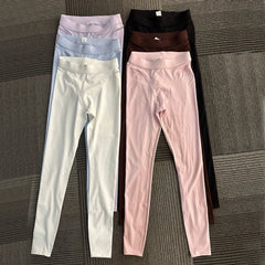 Four pairs of leggings in different colors on a textured surface