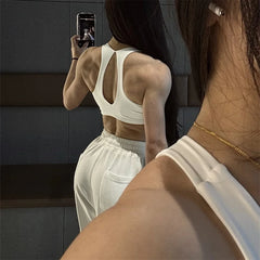 Person taking a mirror selfie wearing a white sports bra and shorts.