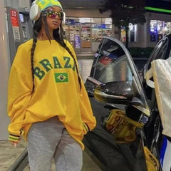 Person wearing a yellow 'BRAZIL' sweatshirt at a gas station.