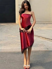 Woman wearing a burgundy satin dress standing on a street.