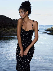 A woman wearing a stylish polka dot midi dress, showing off its flattering fit and playful design.