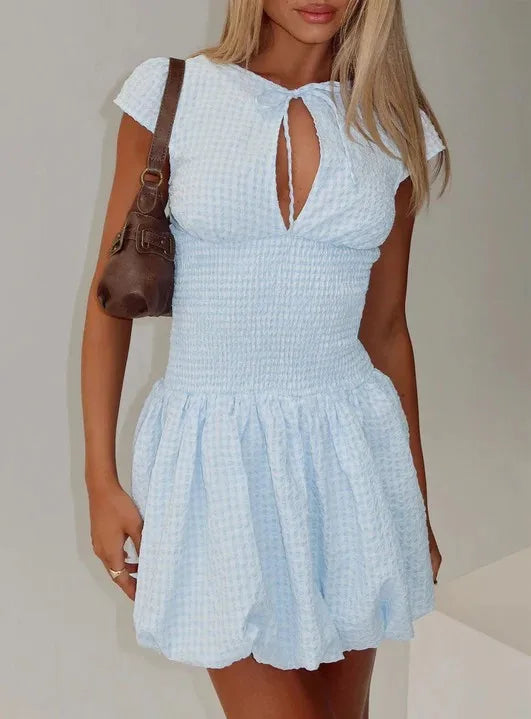 Light blue dress worn by a person with a brown handbag on a neutral background
