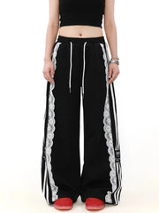 Black track pants with white lace trim and stripes worn by a person 