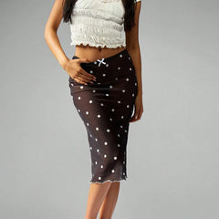 Brown skirt with white polka dots worn by a person on a gray background
