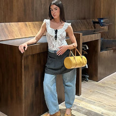 Woman standing in a modern interior setting holding a yellow handbag.