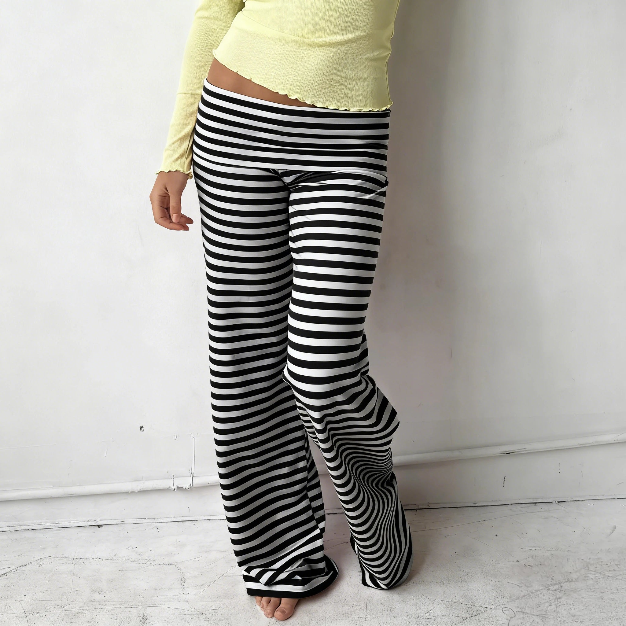 Person wearing black and white striped pants against a plain background