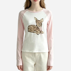 A woman wearing a long-sleeve raglan top with a white body, light pink sleeves, and a central graphic of a brown deer with a pink bow. The Anivia brand logo is visible in the top left corner.