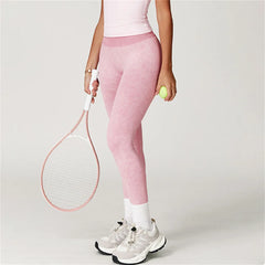 Person wearing pink leggings holding a tennis racket and ball 