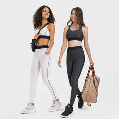 Two women wearing black and white athletic outfits with a beige bag