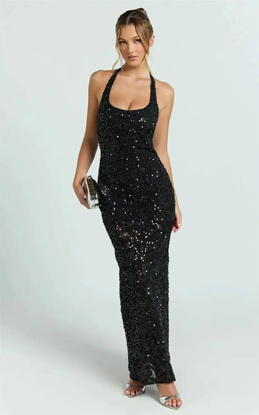 Woman wearing a black sequin halter maxi dress and holding a silver clutch.