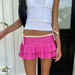Person wearing a white top and pink skirt with a blurred background