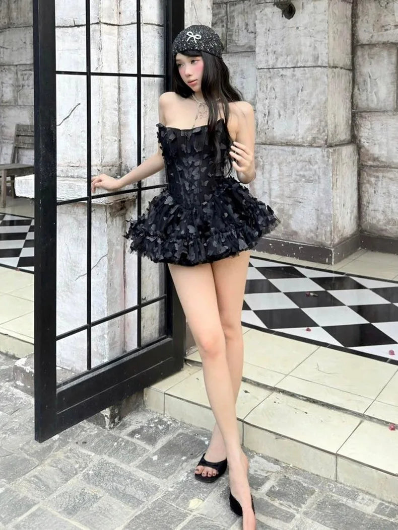 Women's black strapless mini dress with a fitted bodice and a voluminous, layered ruffled skirt.
