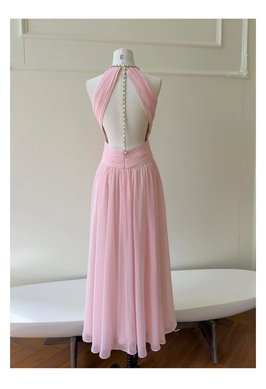 Back view of a pink maxi dress showcasing an open back design with a striking rhinestone chain closure.